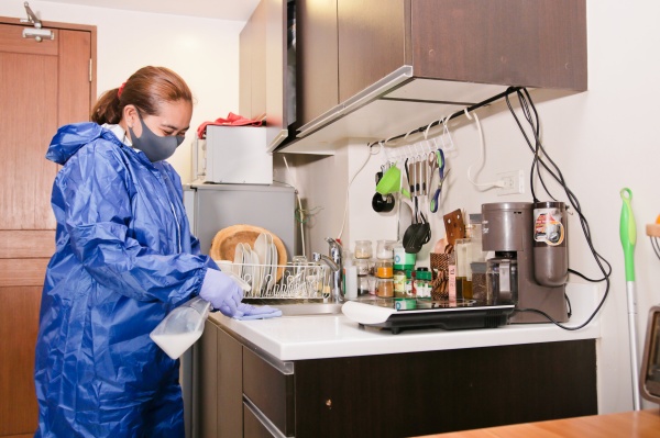 Woman holding a spray bottle cleaning the counter in kitchen